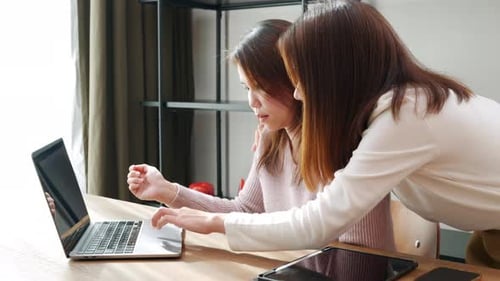 Asian Mother and Teenage Daughter Looking at Laptop Computer at Home Office