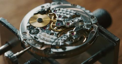 Slow motion close up of a professional watchmaker repairer working on a luxury mechanism watch gea