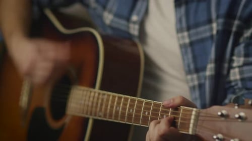 Man plays guitar while rehearsing a song in a home studio in a garage.