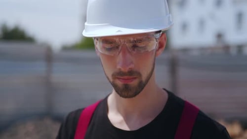 Close Up Shot of Professional Construction Worker Wearing Hard Hat and Safety Glasses Holds Tablet