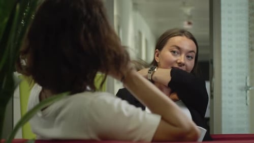 Zwei Frauen in Sesseln führen ein entspanntes Gespräch. Kaffee, Lachen, Trost
