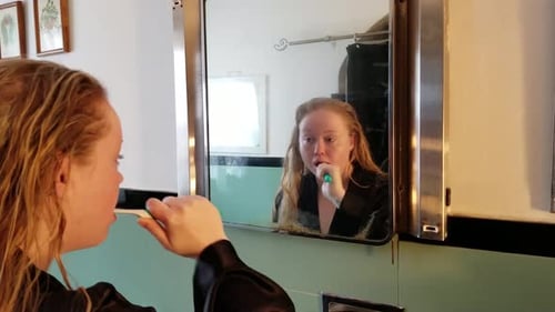 Woman Brushing Teeth in Bathroom Mirror