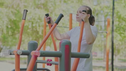 Woman Working Out on Outdoor Exercise Equipment in the Park