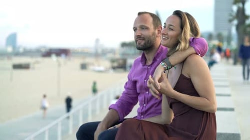 Attractive couple chatting happily on a sunny beachfront promenade in the city