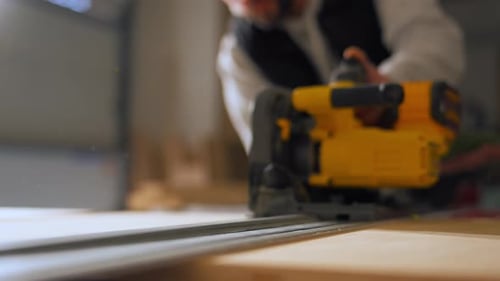 Carpenter Using Electric Circular Saw to Cut Wood During Construction or Renovation Work Close View