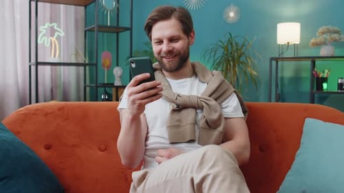 Man Sitting on Couch Reacts to Phone Content