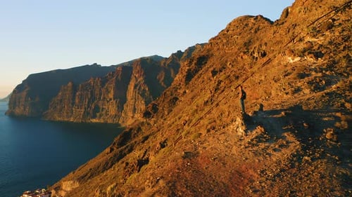Man Tourist Backpacker on Mountain Top with Ocean View at Sunset