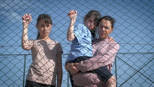 Mother and Children Hold Chain-Link Fence