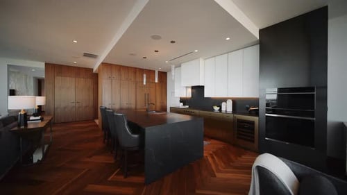Spacious, modern kitchen with a black island, wood cabinetry, and minimalist design in a luxury apar