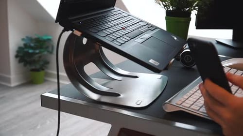 Working from home on a laptop on a rainy day, scrolling social media on phone