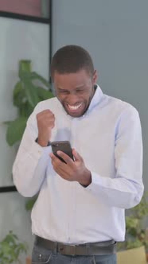 Excited Man Celebrates Success While Using Smartphone