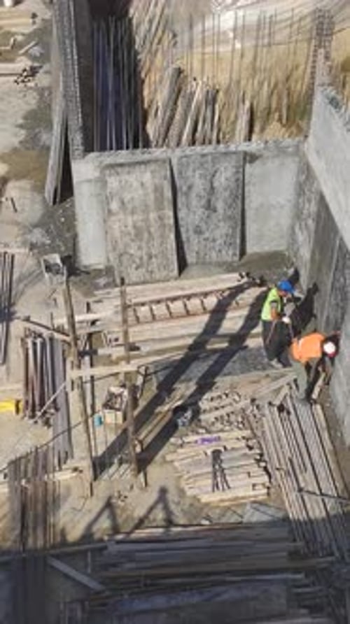 Vídeo vertical: trabajadores cualificados construyen paredes en una obra de construcción muy transitada para destacar el progreso y