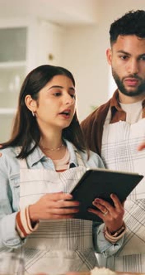 Young Couple Cooking Together Using Tablet in Kitchen