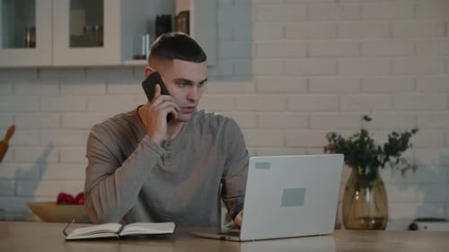 A Male Freelancer with a Short Haircut Works Remotely on a Laptop and Discusses with the Employer on