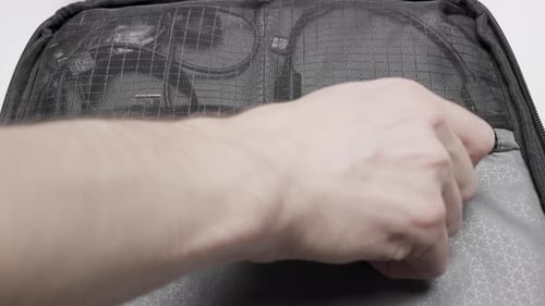 Close up of a male hand opens zipper lock of mesh pocket