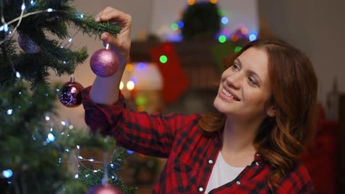 Woman Decorating Christmas Tree with Pink Ornament