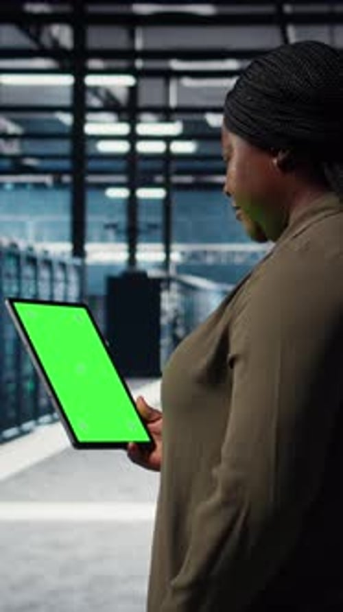 Вертикальный видеоинженер на работе использует планшет с изолированным экраном в центре обработки данных для проверки оборудования