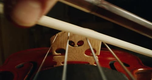 Cinematic alternative macro shot of master artisan luthier or violinist playing with bow on handma