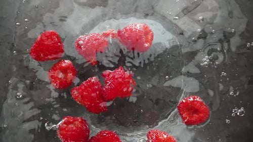 Vibrant Raspberries Floating in Clear Water Bowl