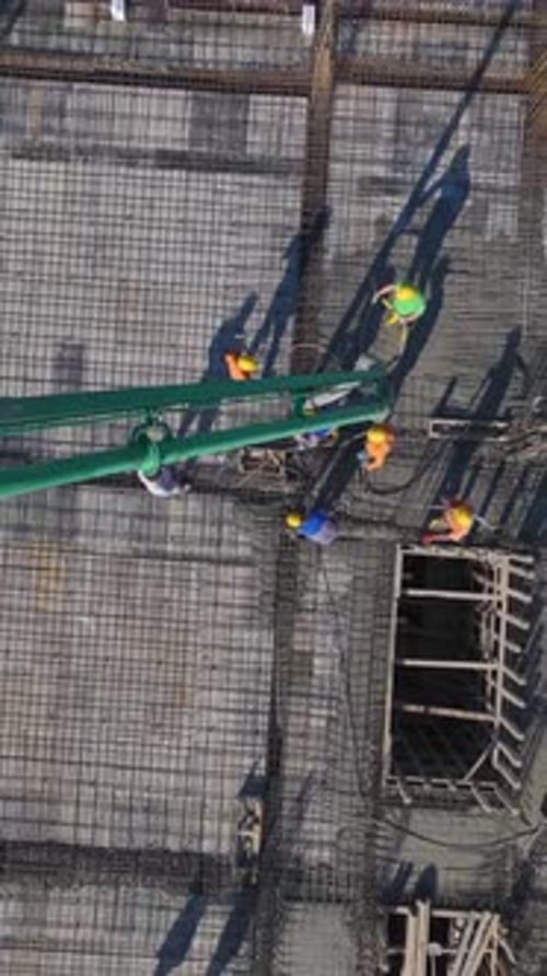 Vertical Video of Residential Construction With Workers Pouring Concrete and a Crane Installing