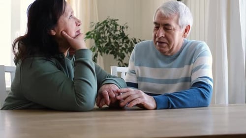 Senior Couple Holding Hands and Talking at Table