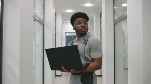 Young Adult Using Laptop in Bright Hallway