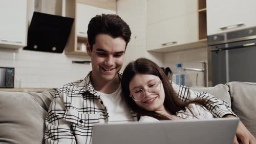 Young Couple Relaxing on Couch with Laptop