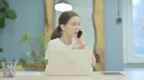 Angry Woman Arguing on Phone at Her Desk