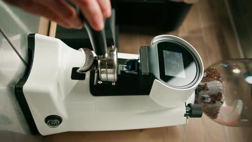 Professional barista worker uses grinder to grind fresh coffee beans to make hot drink coffee shop