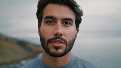 Attractive Bearded Man Looking Camera at Cloudy Seascape Backdrop Close Up. Portrait