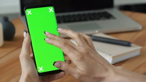 Person hält Handy mit Greenscreen-Display in der Hand und Frau machen eine Geste. Nahaufnahme mit...