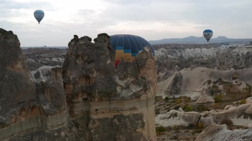 Heißluftballons fliegen bei Sonnenaufgang über die Berglandschaft von Kappadokien in der Türkei - Drohnenaufnahme aus der Luft