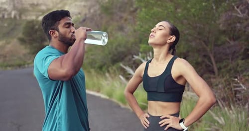 Fitness, man and woman on break drinking water on outdoor path, running exercise