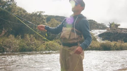 Man Fishing in Rushing River with Waterfall