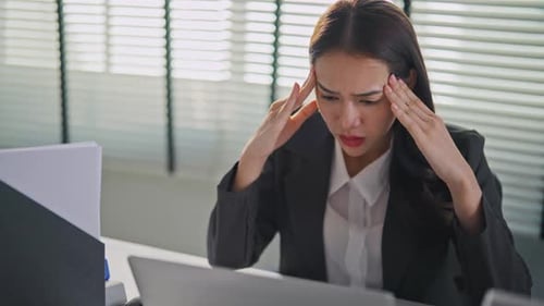 Frustrated Asian young businesswoman overwork late in office workplace.