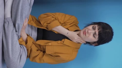Vertikales Video einer kranken jungen Frau, die hustet und sich an eine Wand lehnt. Hoffnungslos
.