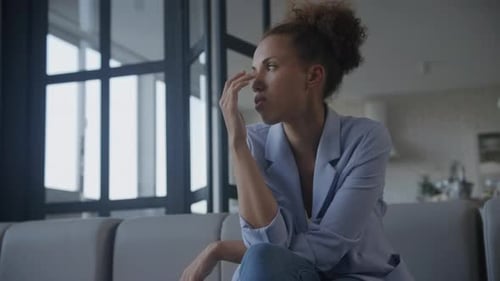 Woman Sitting on Sofa, Deep in Thought