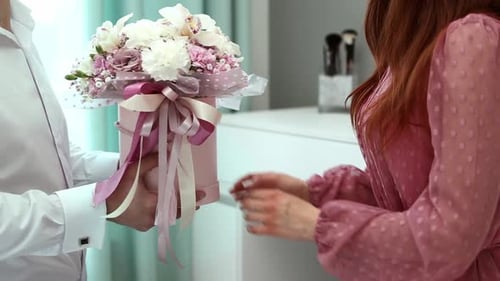 Man Gives Box of Flowers to a Woman Indoors