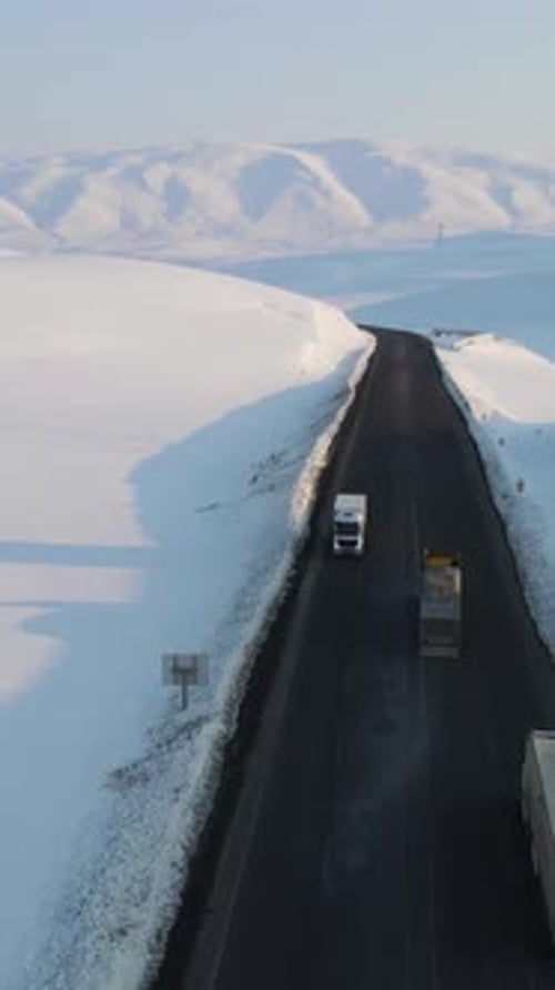 Vehicles Driving on Road Through Snowy Landscape
