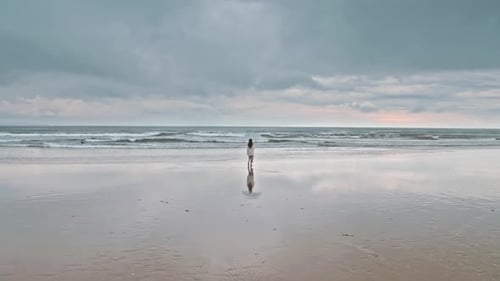 Woman Walking On The Beach With An Umbrella Aerial