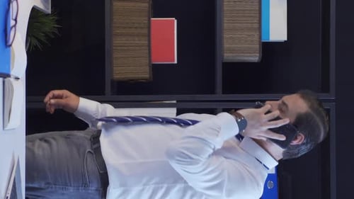 Vertical Video of Businessman talking on the phone standing in the office.