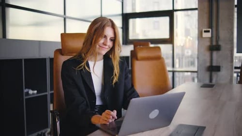 A Young Professional Woman is Diligently Working on Her Laptop in a Stylish and Modern Office