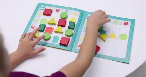 Little girl playing with educational toy at white table, closeup