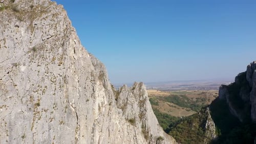 Flying through vertical limestone walls in a deep gorge, canyon, rock climbing aerial