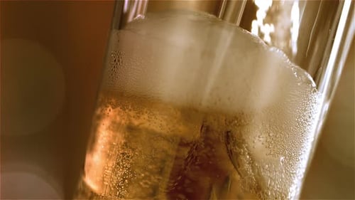 Golden Beer Pouring into Glass with Ice