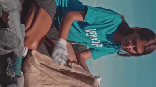 Young Caucasian Women and Men Work Together to Collect Garbage From Land
