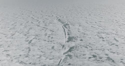 Drone approach to crack in frozen lake ice winter aerial landscape with dangerous natural surface