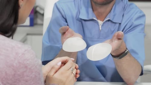 Plastic Surgeon Presenting Breast Implants to Attentive Female Patient