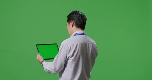Back View Of Asian Business Man Using Tablet An Looking Around On Green Screen Background