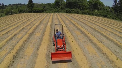 Aerial of Man Driving Tractor on Farm